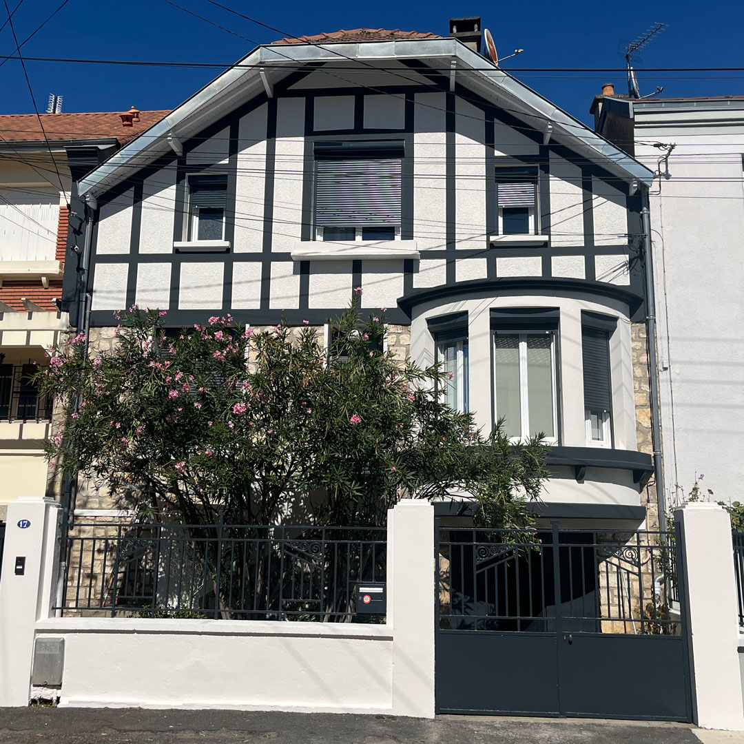 Façade rénovée, crépi clair, colombages sombres, murette et portail repeints
